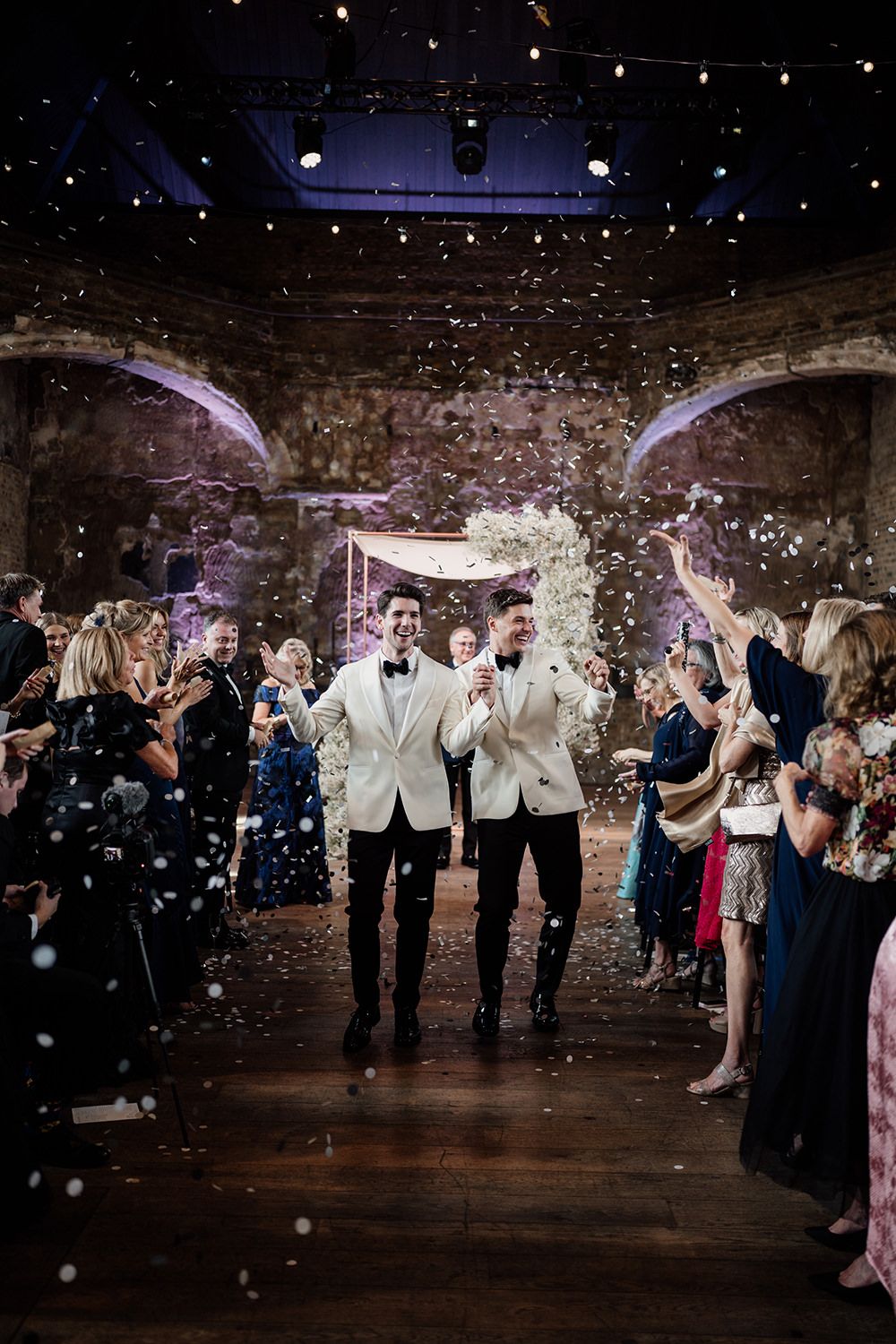 Wedding guests celebrate with white sparklers in an indoor brick venue creating magical glowing moments.