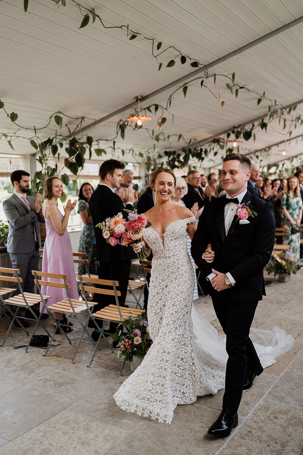 Bride and Groom holding hands and smiling as they leave their wedding ceremony at The Garden Rooms, kin house.