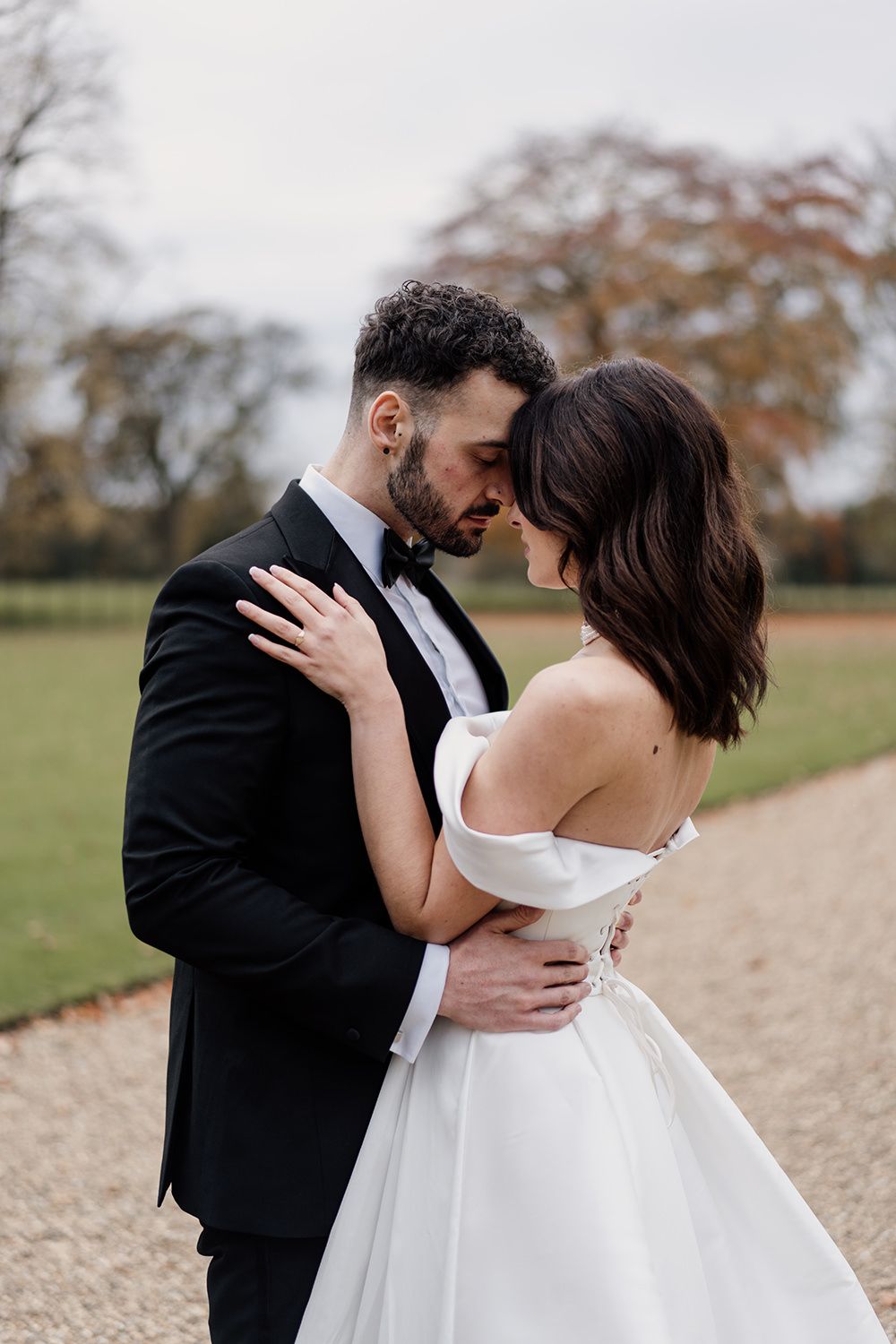 Bride and groom holding hands, smiling, laughing while working through the grounds of Rise Hall.