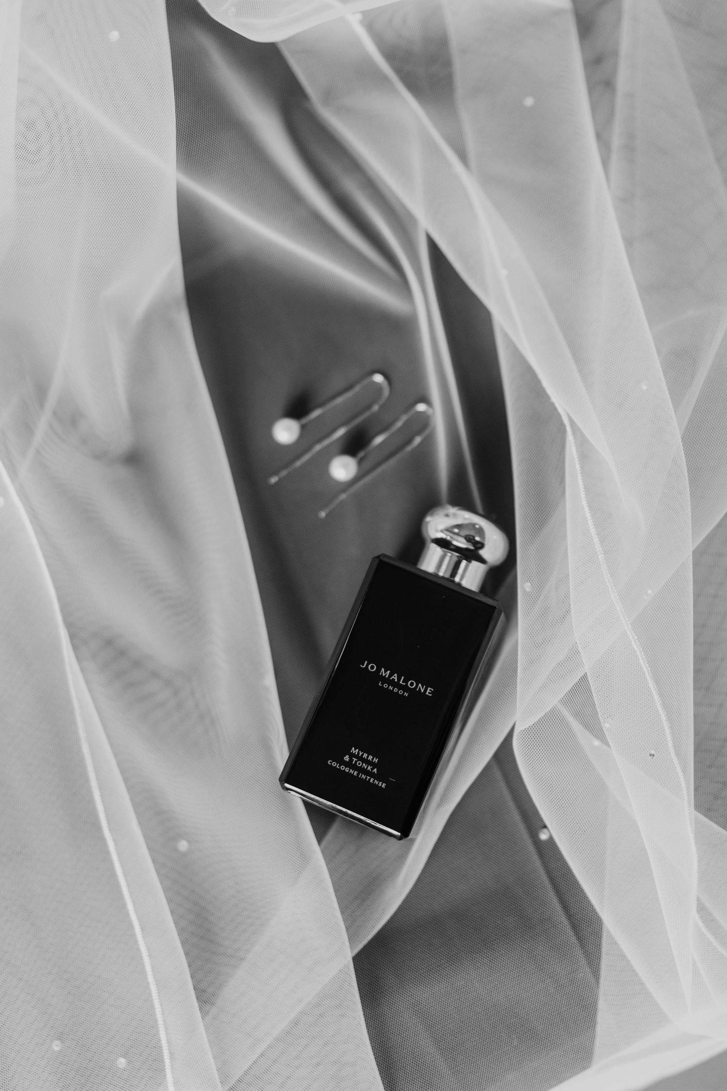Black and white perfume bottle styled with sheer fabric.