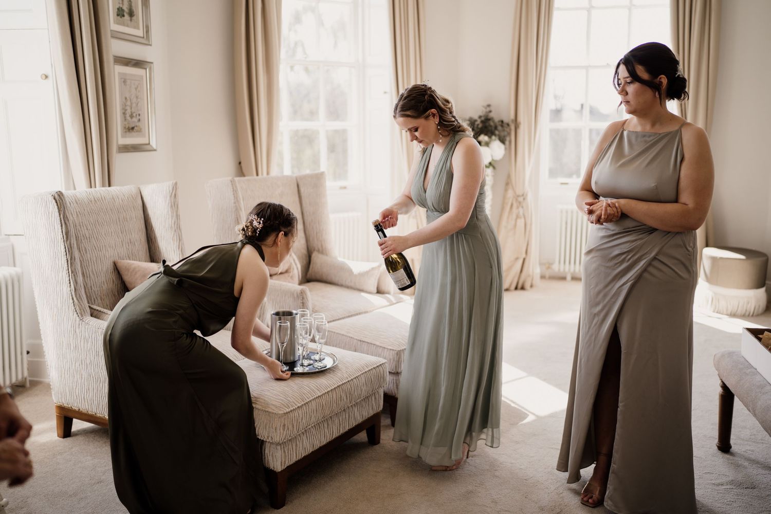 Bridesmaids pouring prosecco to celebrate with windows in the background.