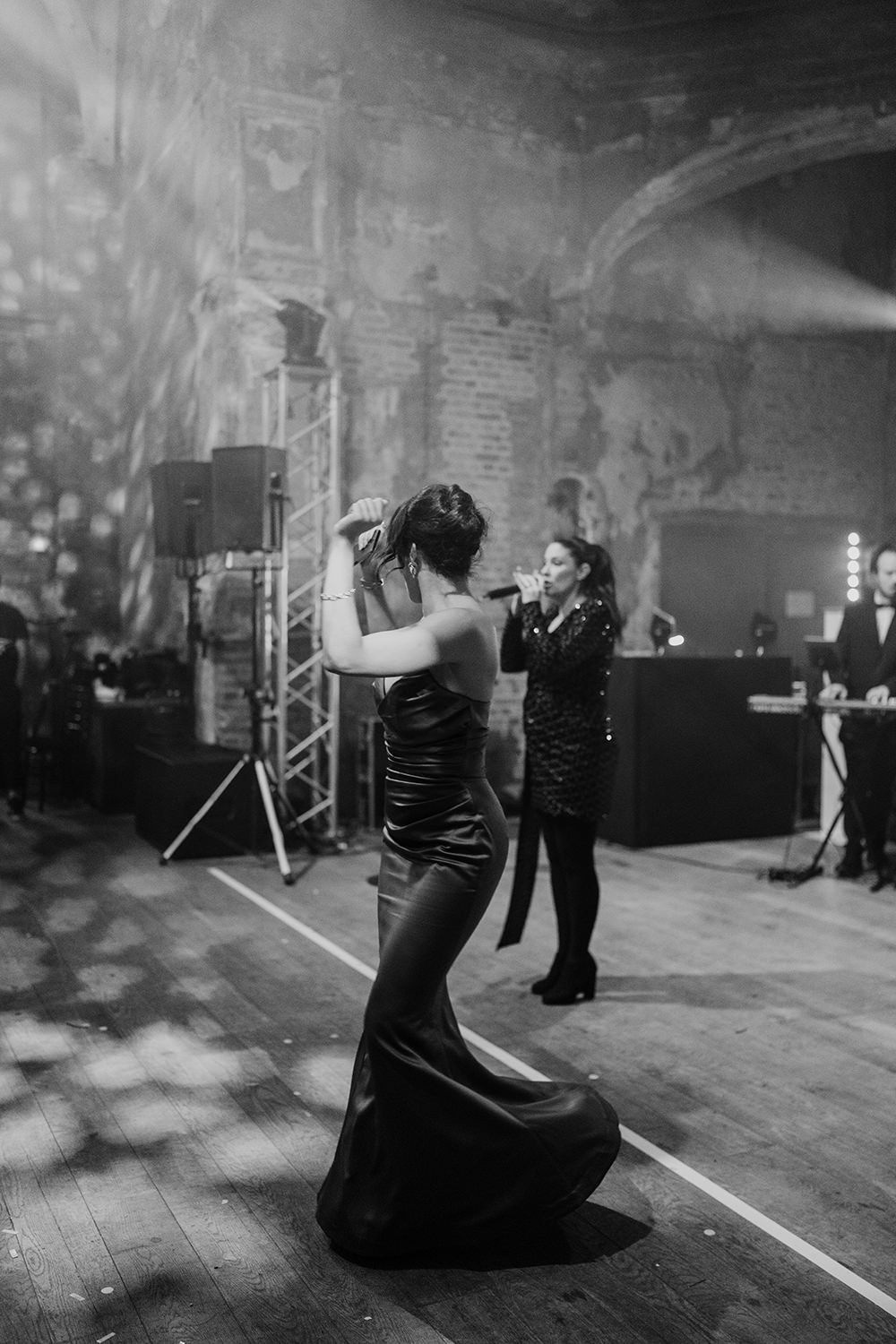 Wedding guest dancing in front of a live band, her arms are in the air and her dress is flowing.