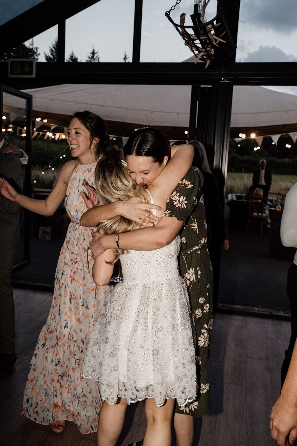 Bride and her friend hugging, the shot is lit with a flash on the evening of the wedding.