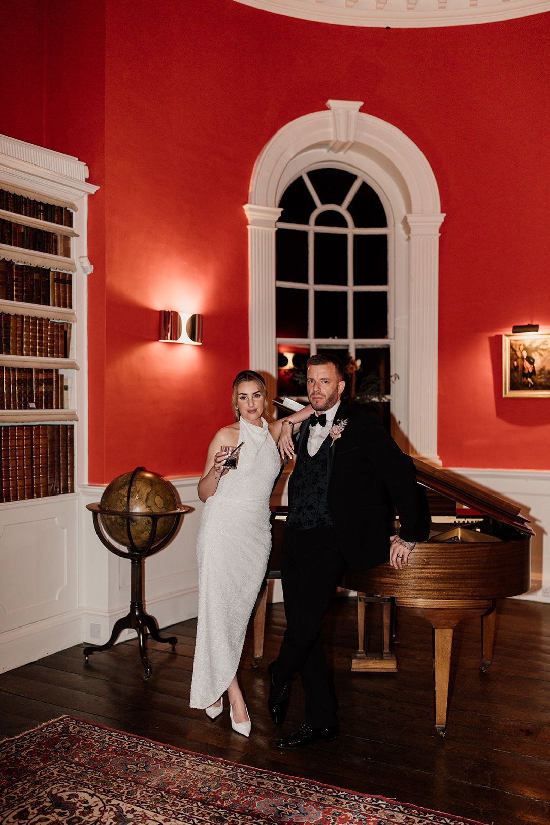 Two figures dance together in an elegant room with red walls and arched windows.