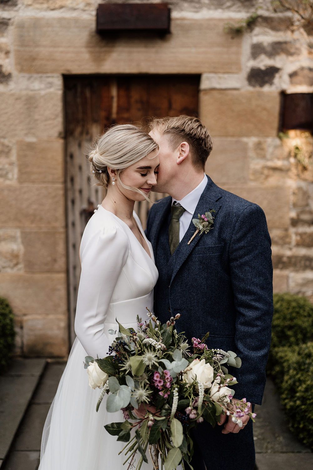 Bride and groom kissing with Healey Barn in the background.