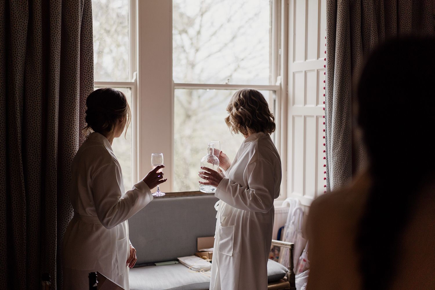 Bridesmaids stood looking out of the window at healey hall.