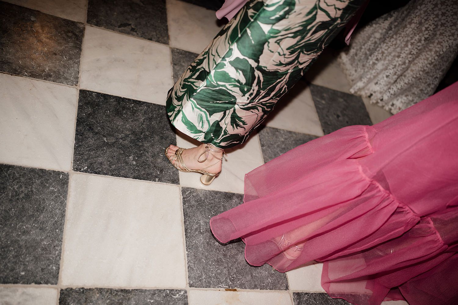 Wedding guests dancing capturing their colourful dresses on a black and white checkered dancefloor.