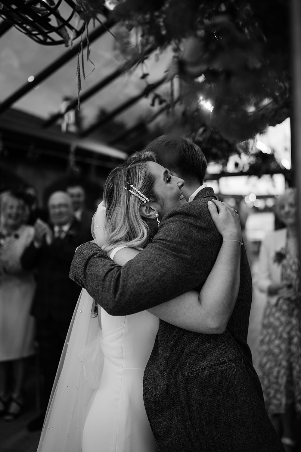 Image of bride and groom hugging after their wedding ceremony, bride is wearing white.