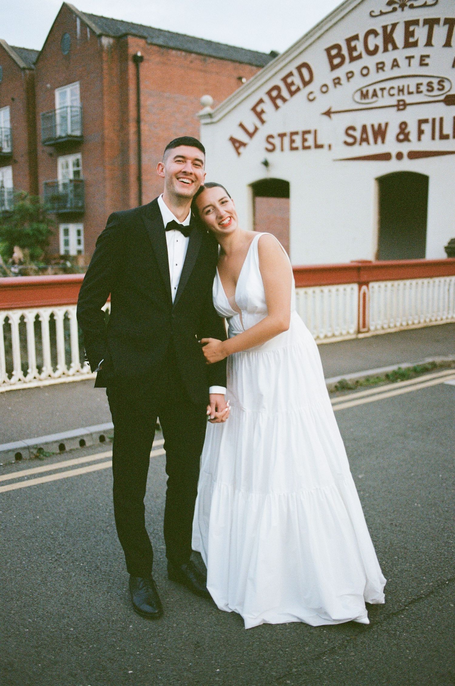 Wedding couple in formal attire pose together outside historic Alfred Beckett Steel building.
