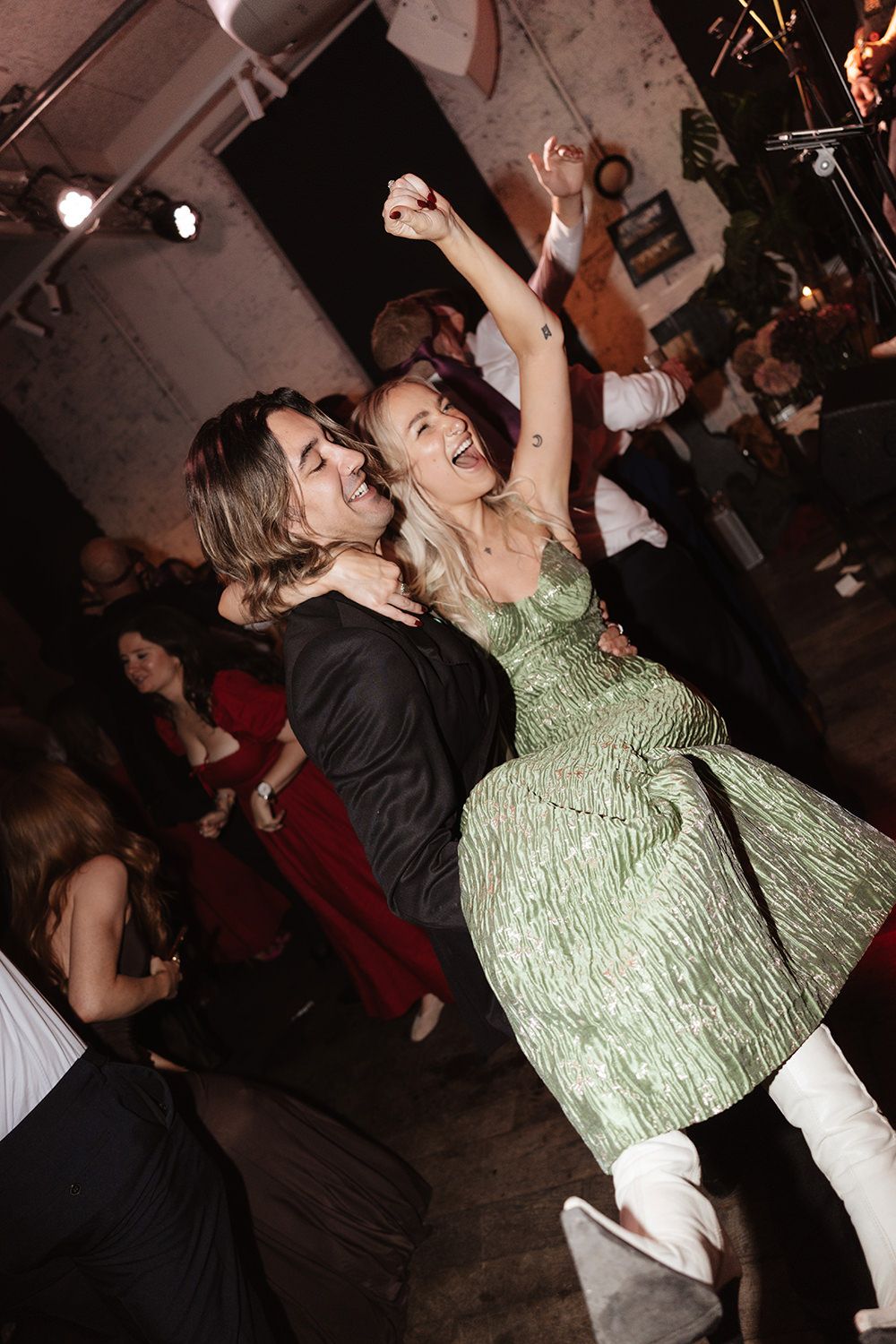 Two dancers perform an energetic dance move at a dimly lit party venue.
