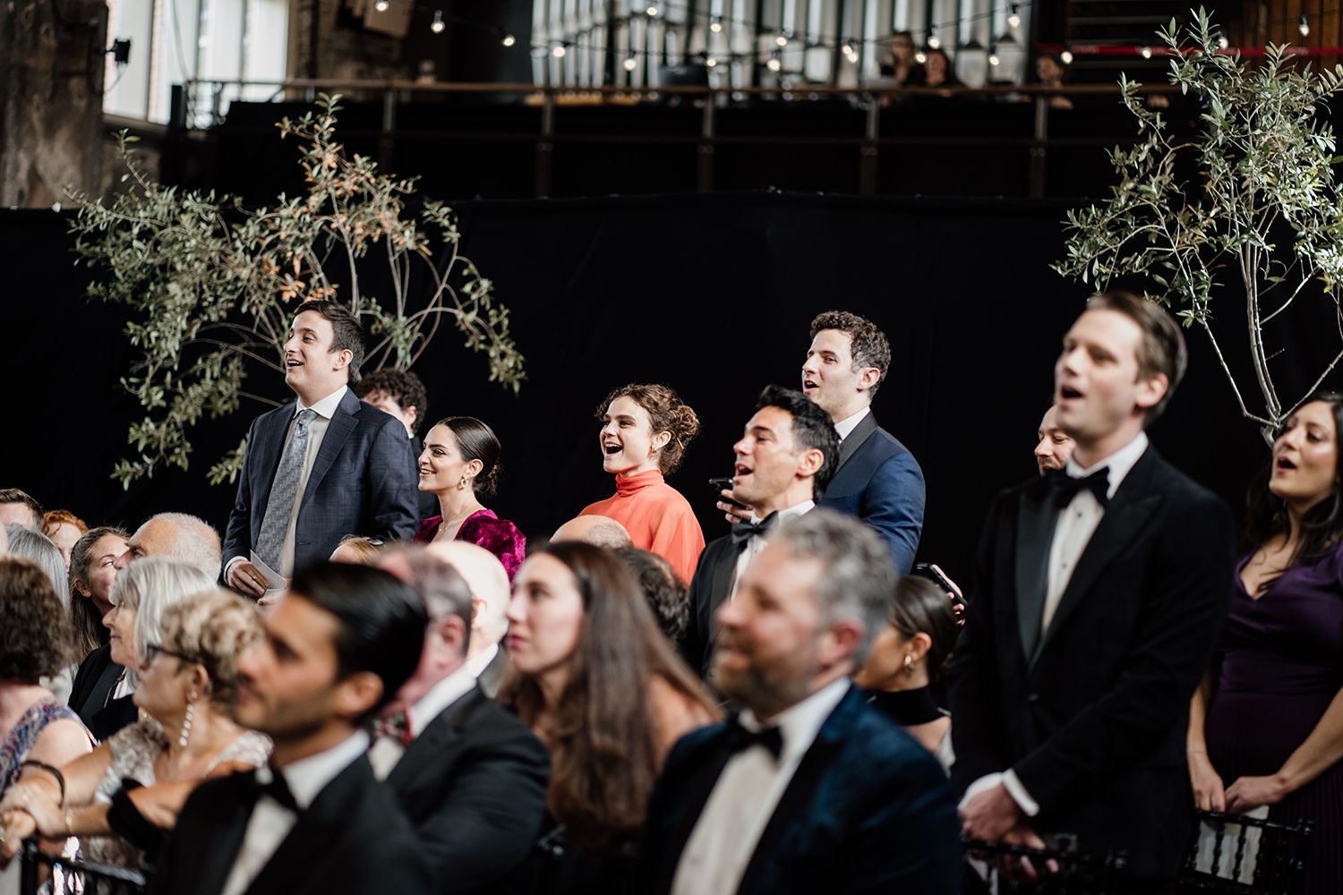 Wedding guests standing singing during the ceremony at Battersea Arts Centre.
