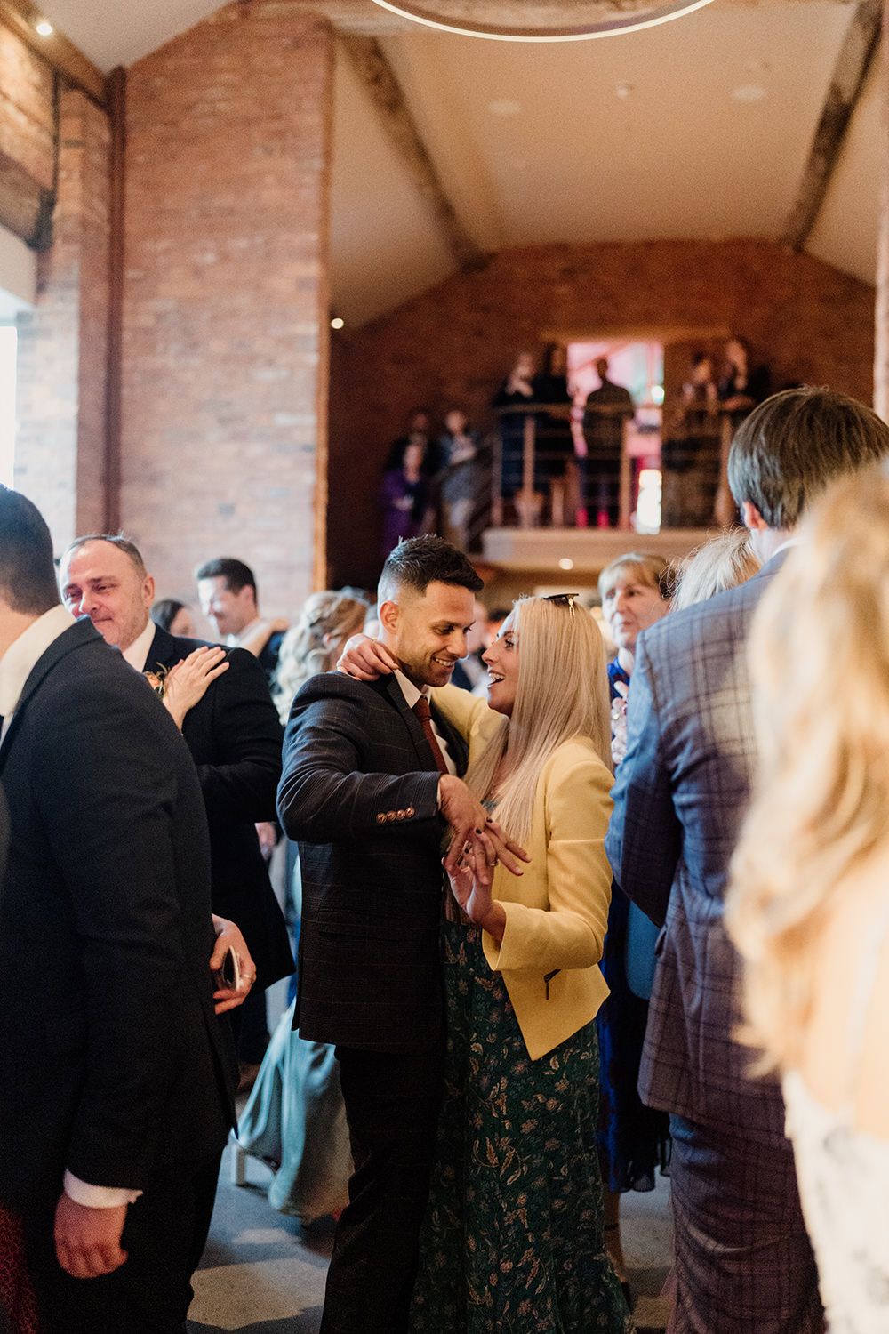 Couple dancing while holding hands with guests surrounding them on the dance floor at The Holford Estate.