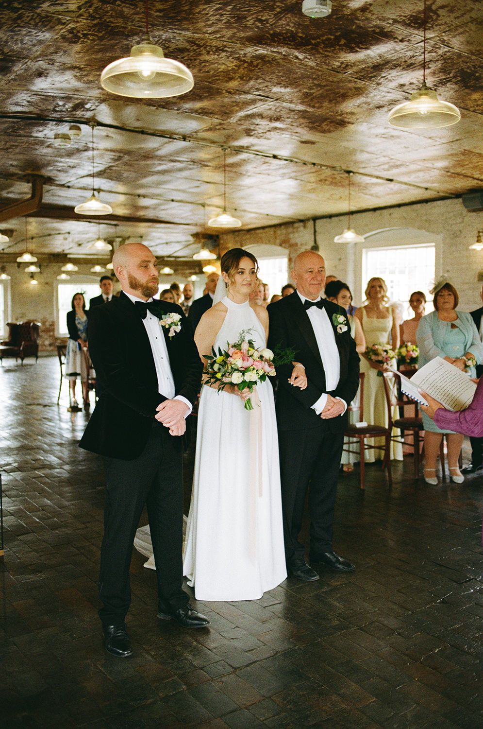 Bride, groom and father of the bride stood at the start of their wedding ceremony.