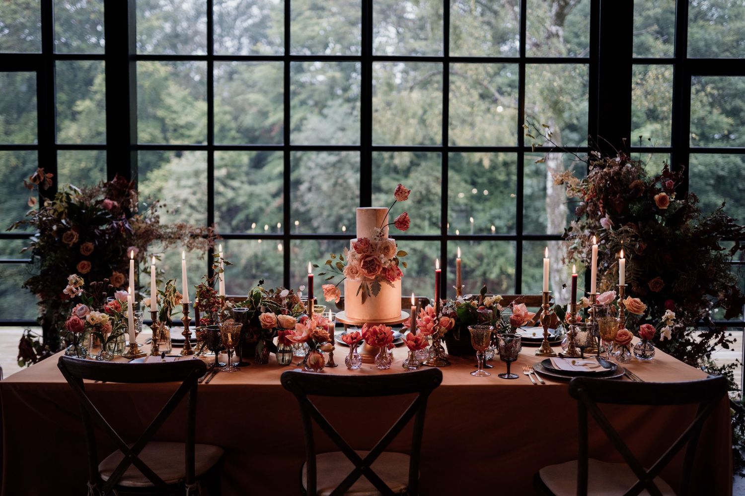 Wedding table styled in autumnal colours, fabrics and rust coloured florals with a wedding cake in the centre.