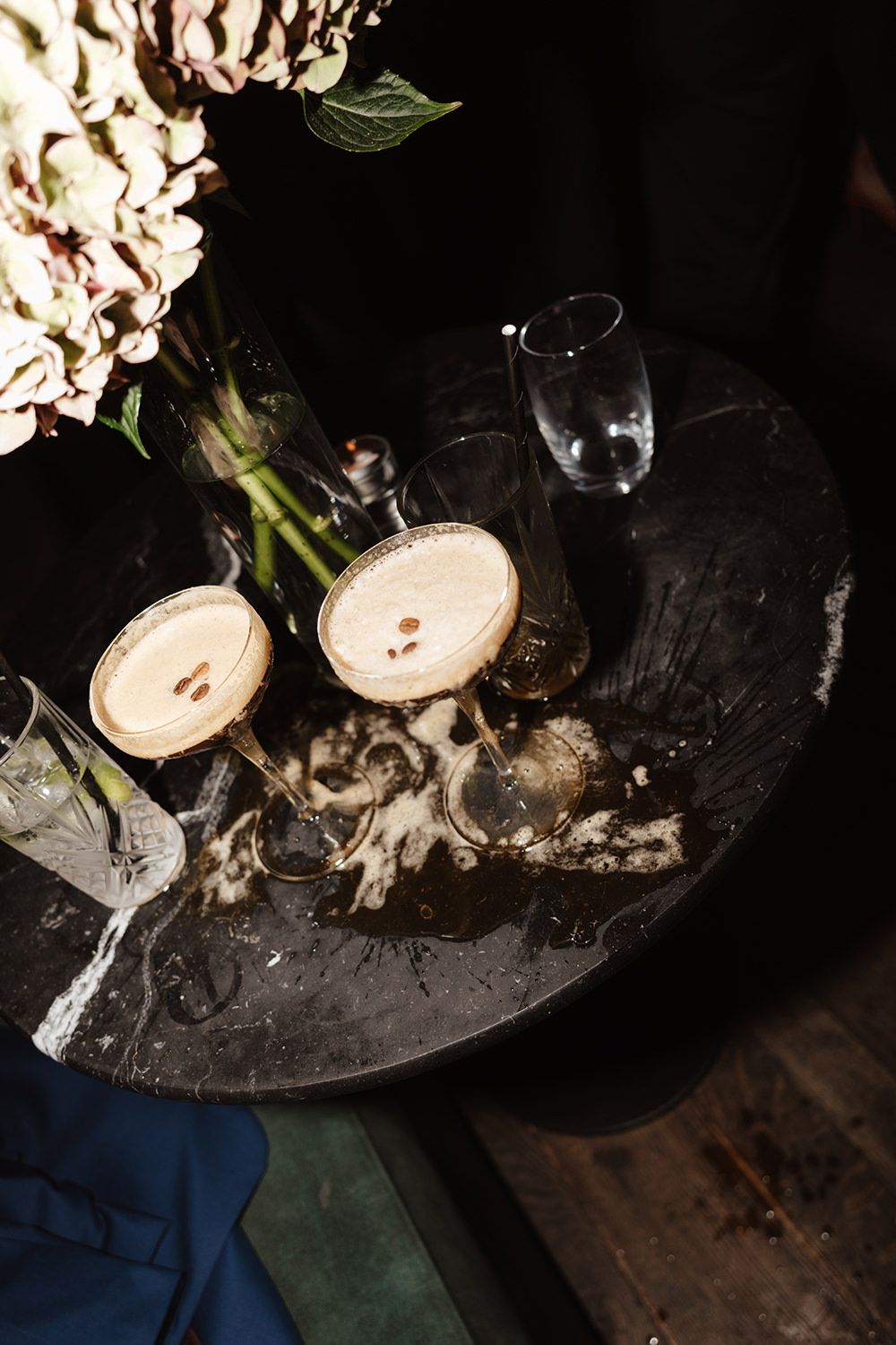 Sliced mushrooms being cooked in a dark pan on a wooden surface with dramatic lighting.