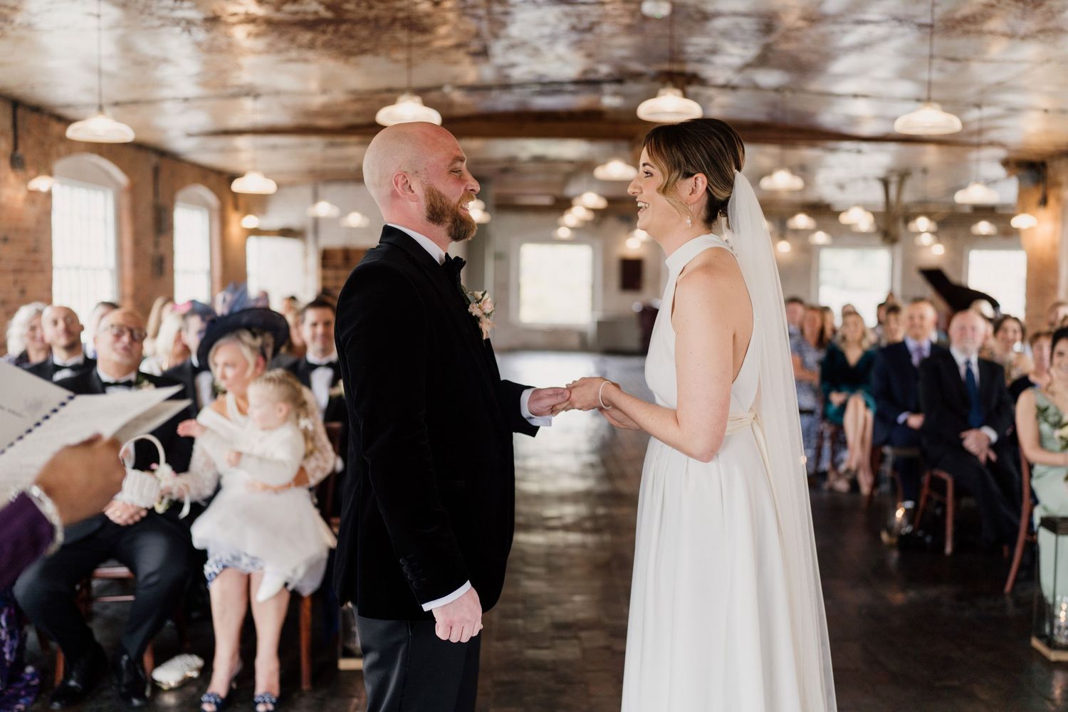 Couple exchanging vows during wedding ceremony in vintage industrial space.