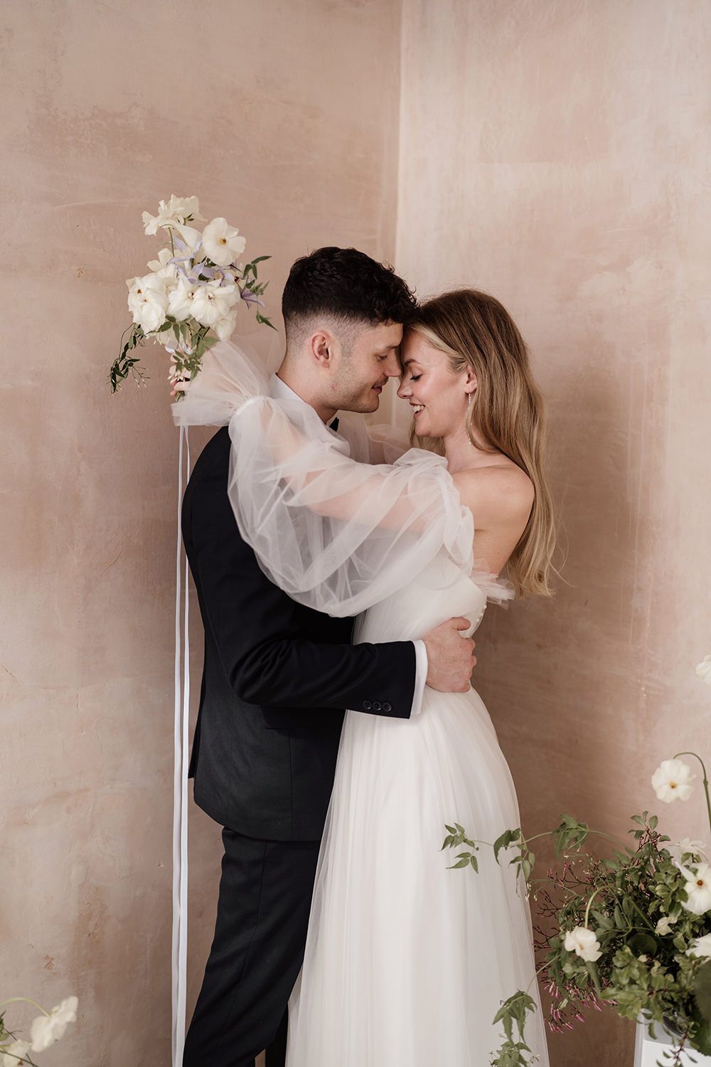 Couple kissing while holding flowers in-front of Ibiza wedding venue.