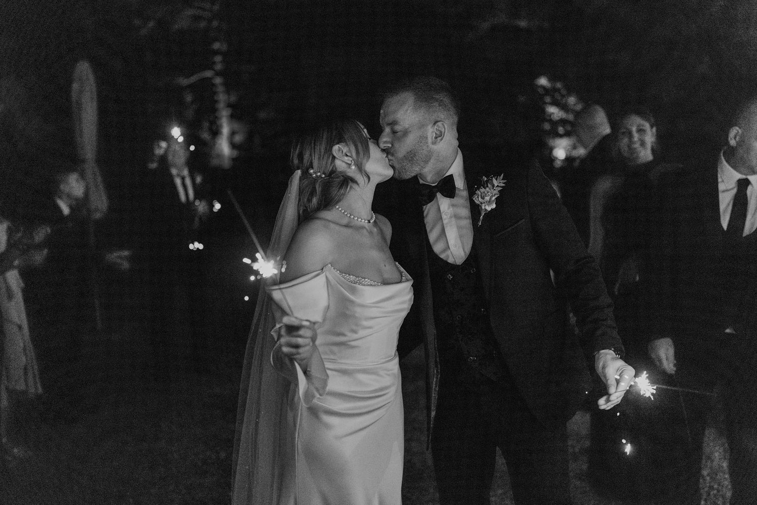 A romantic black and white photo of a couple sharing their first dance at an evening wedding reception.