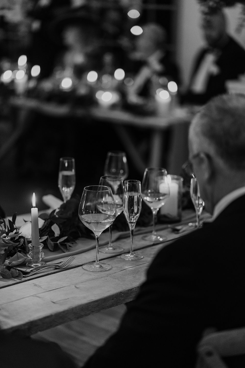 Candid wedding photography: guests sharing a joyful moment around the candlelit dinner table.