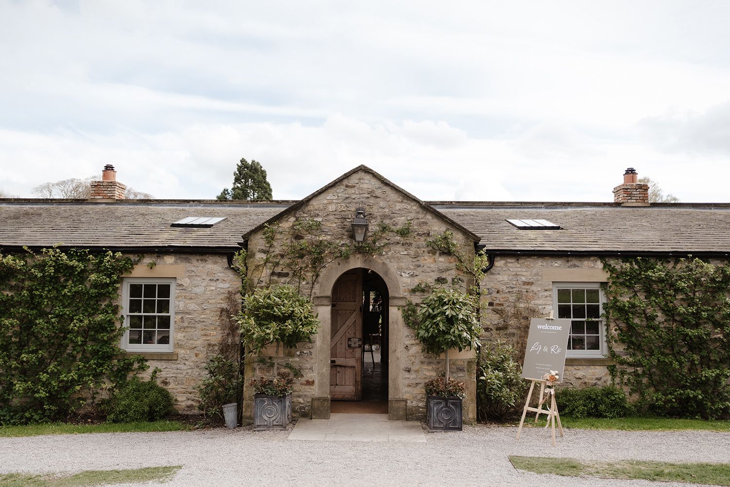 A rustic stone cottage entrance with ivy-covered walls and skylights features a central archway and wooden door.