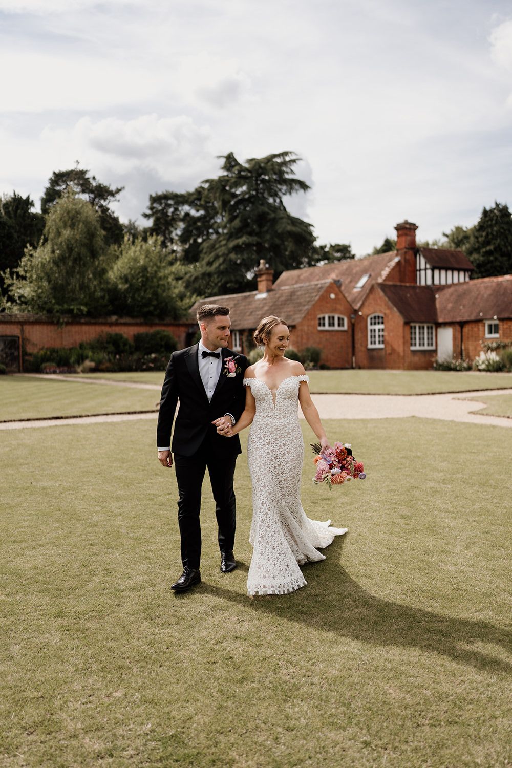 Bride and groom walking through the walled gardens together while smiling and laughing.