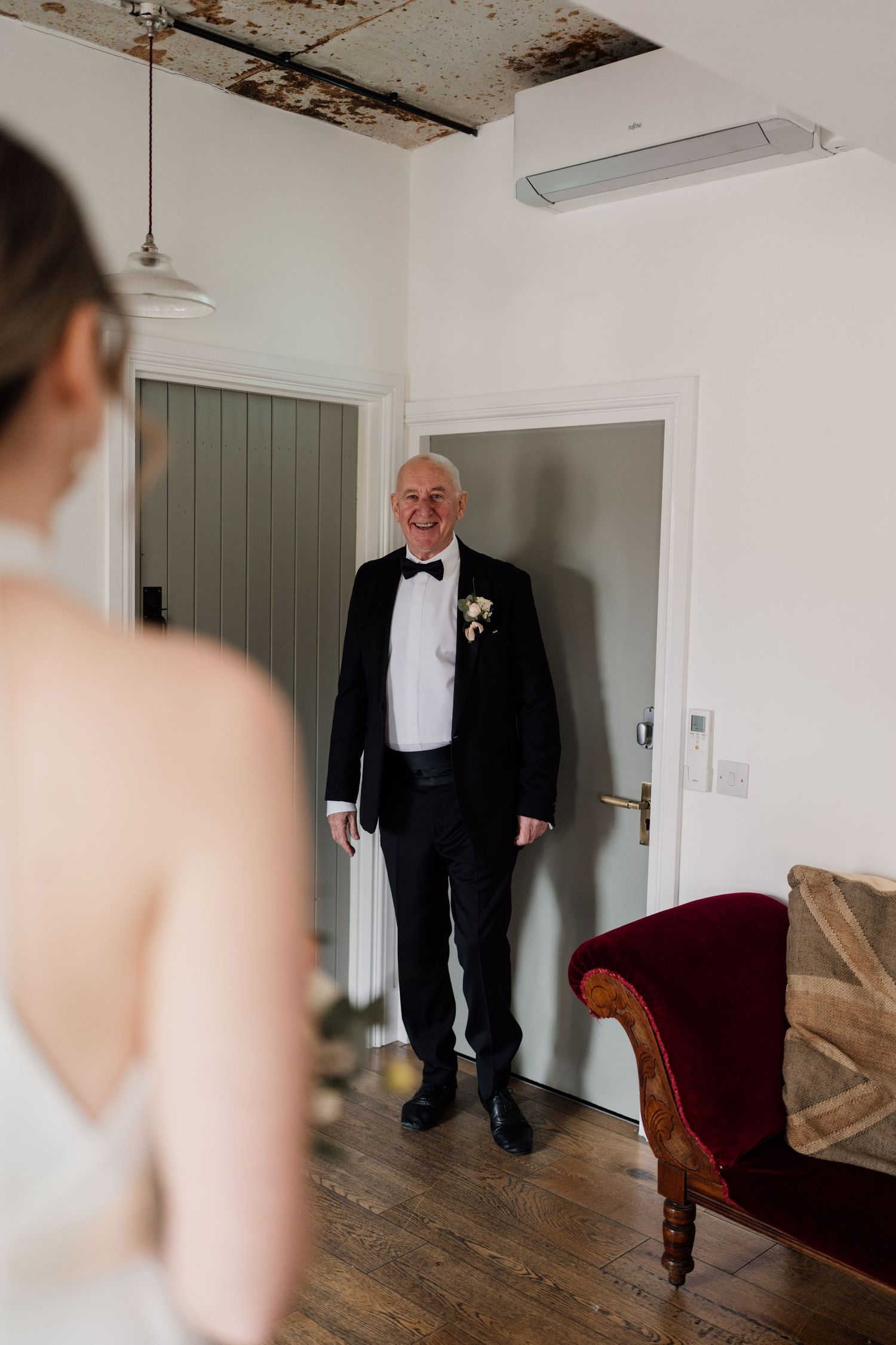Wedding day first look moment in an elegant room with wooden floors and vintage furniture.