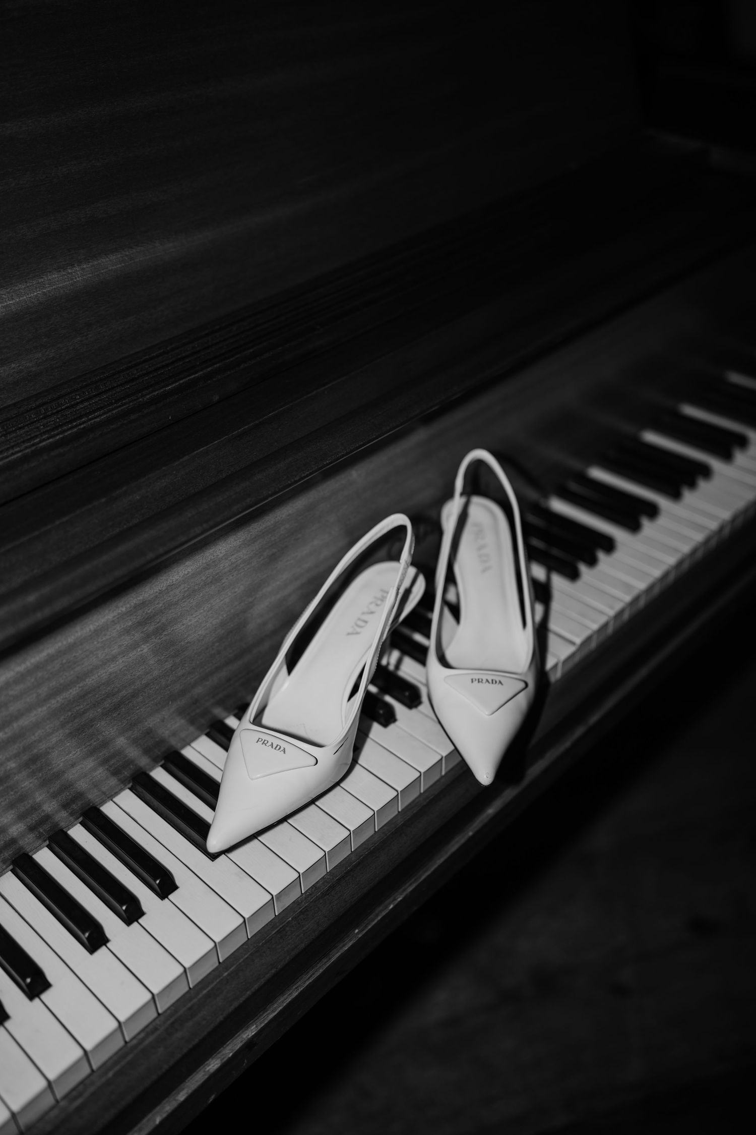A pair of white bridal shoes artistically placed on piano keys in black and white.