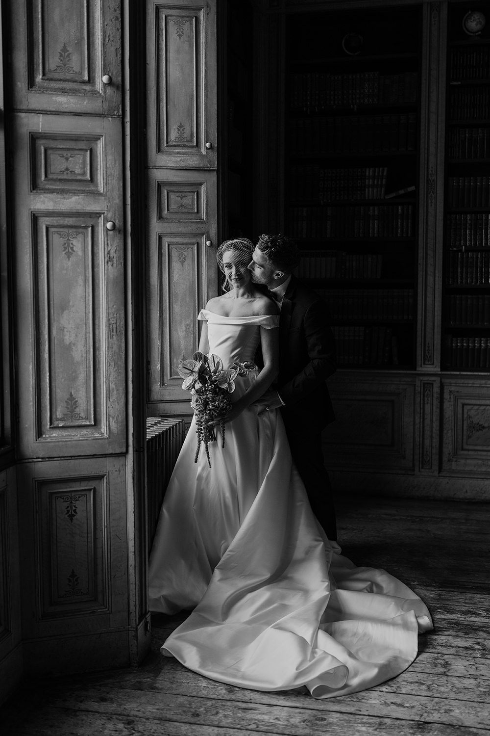 Bride and groom face towards each other while being lit by a grand window at Rise Hall.