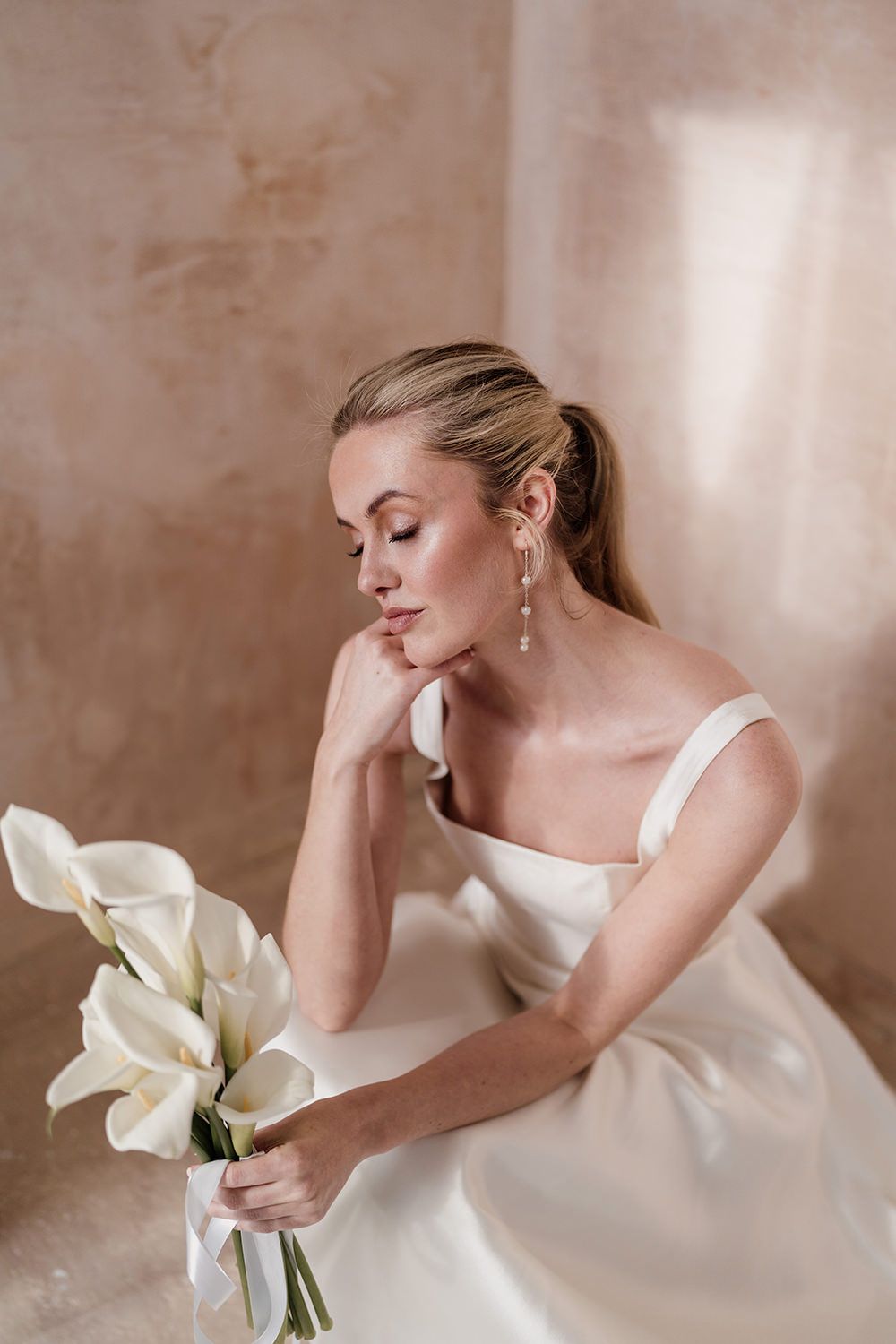Bride sitting while holding white flowers in Ibiza.