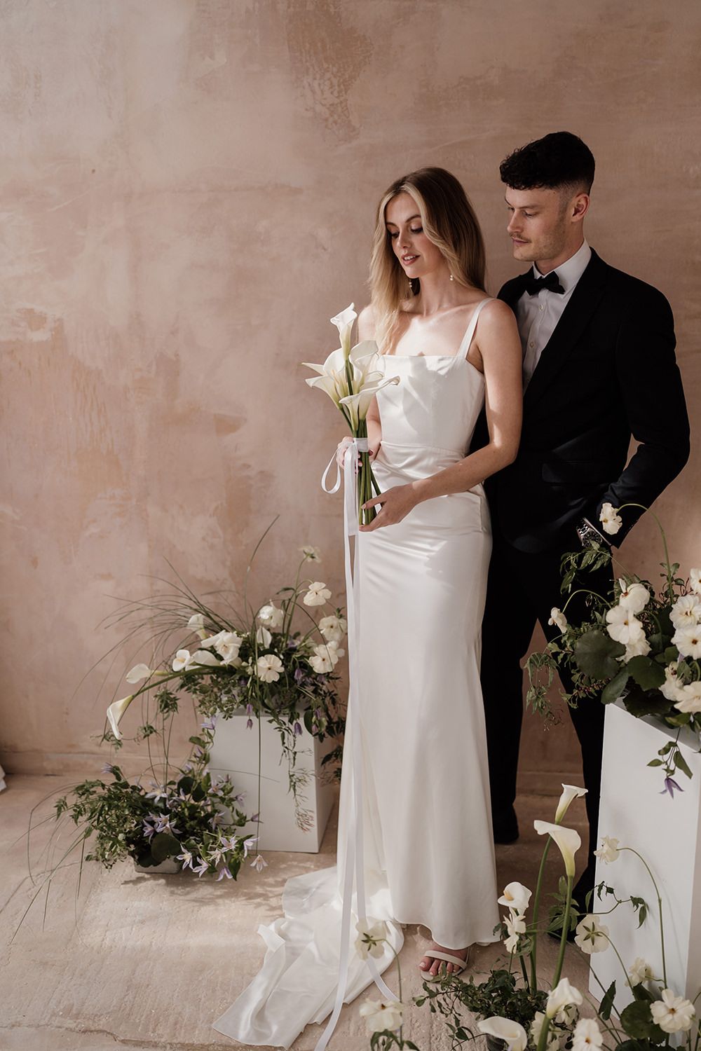 Couple on wedding day with flowers surrounding them.