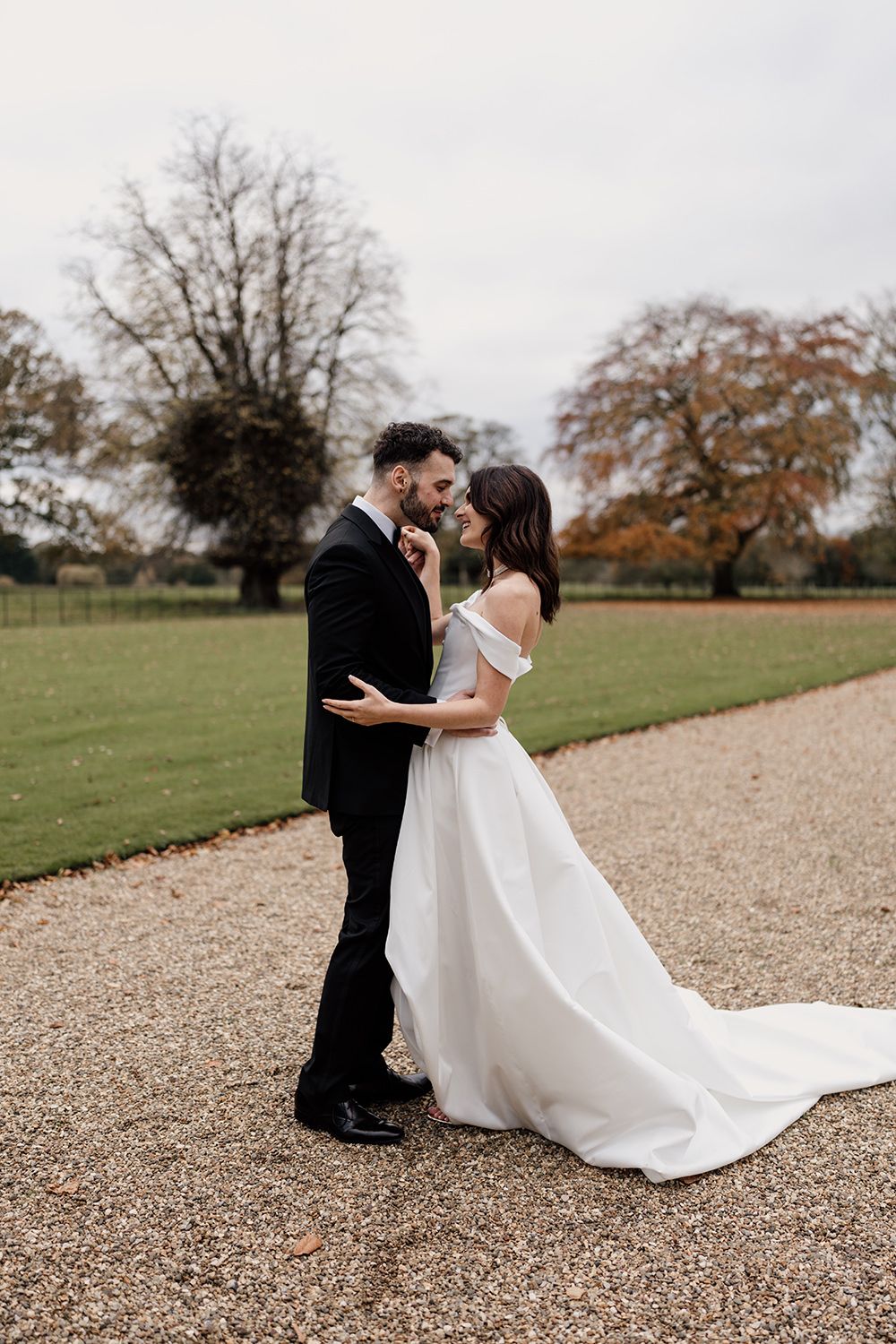 Bride and groom holding hands, smiling, laughing while working through the grounds of Rise Hall.