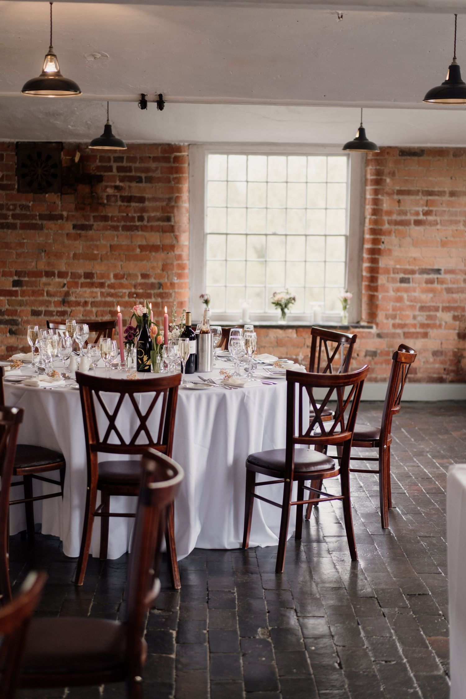 Rustic dining room with exposed brick walls, pendant lights and elegant table settings.