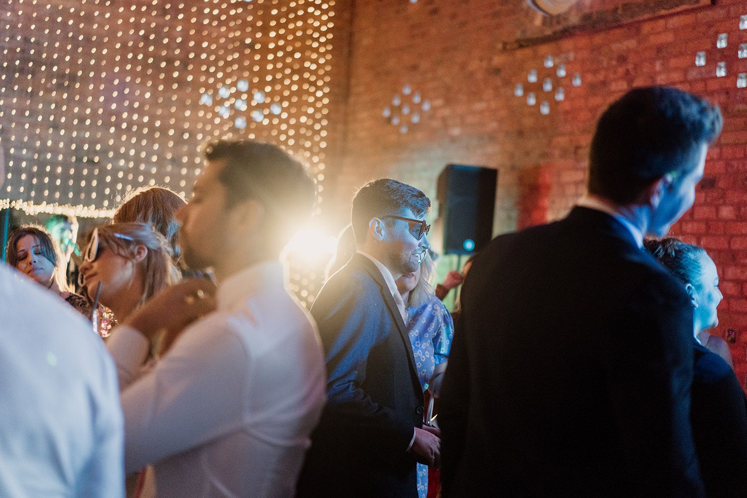 Wedding guests dancing with stage lights behind them.