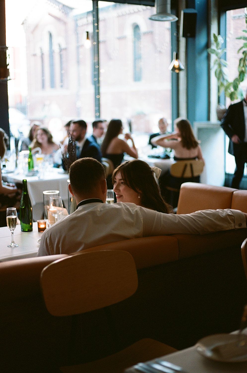 People sitting in a dimly lit restaurant with blurred background and window lighting creating an atmospheric ambiance.