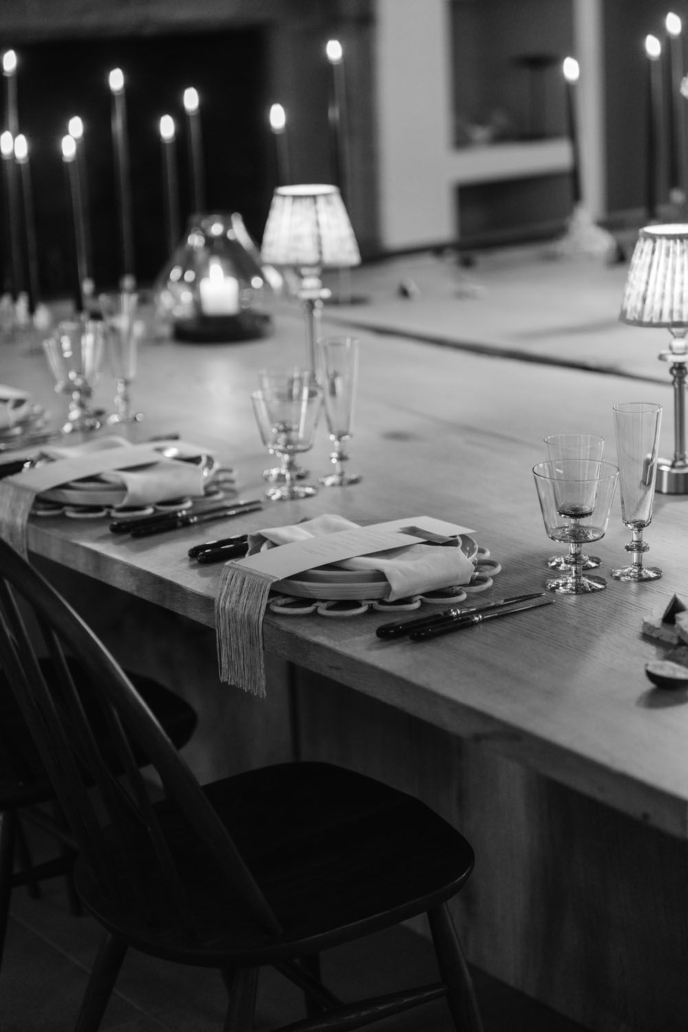 Black and white photo of an elegant dining table set with candles, glassware, and cutlery for a formal dinner.