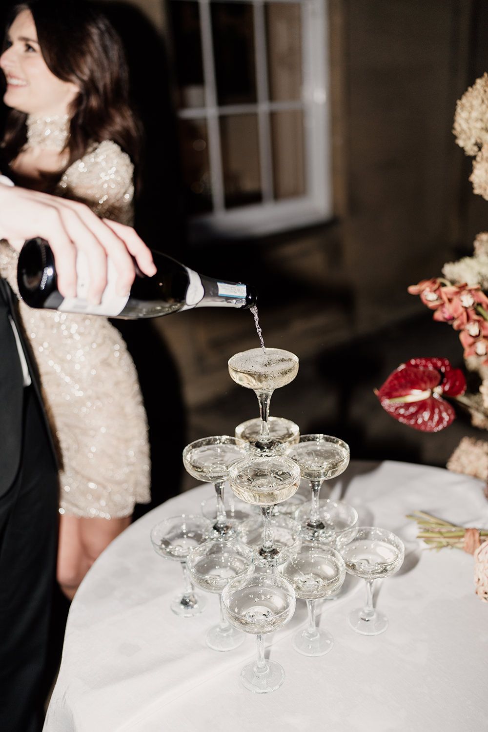 Groom pouring champagne into their champagne tower on their wedding night.