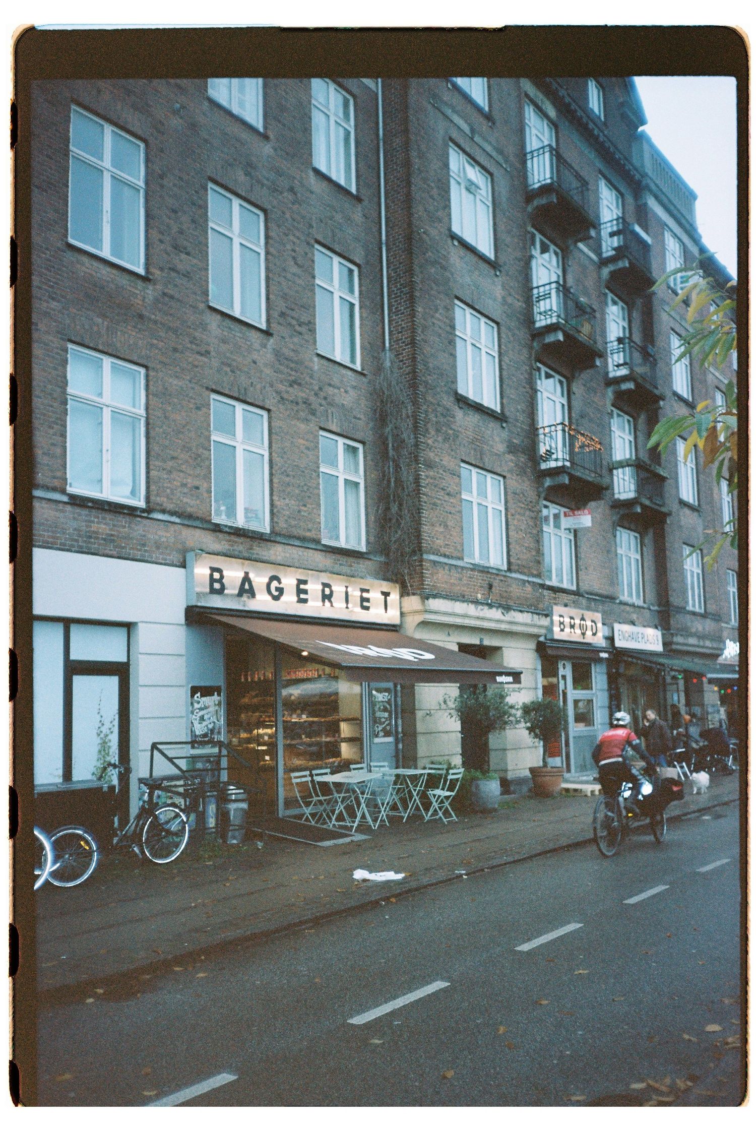 Brick apartment building with Bageriet bakery storefront and street-level seating area.