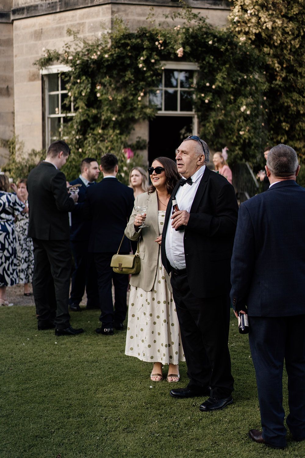 Candid wedding photography: guests enjoying cocktails on the lawn of this luxury UK wedding venue.