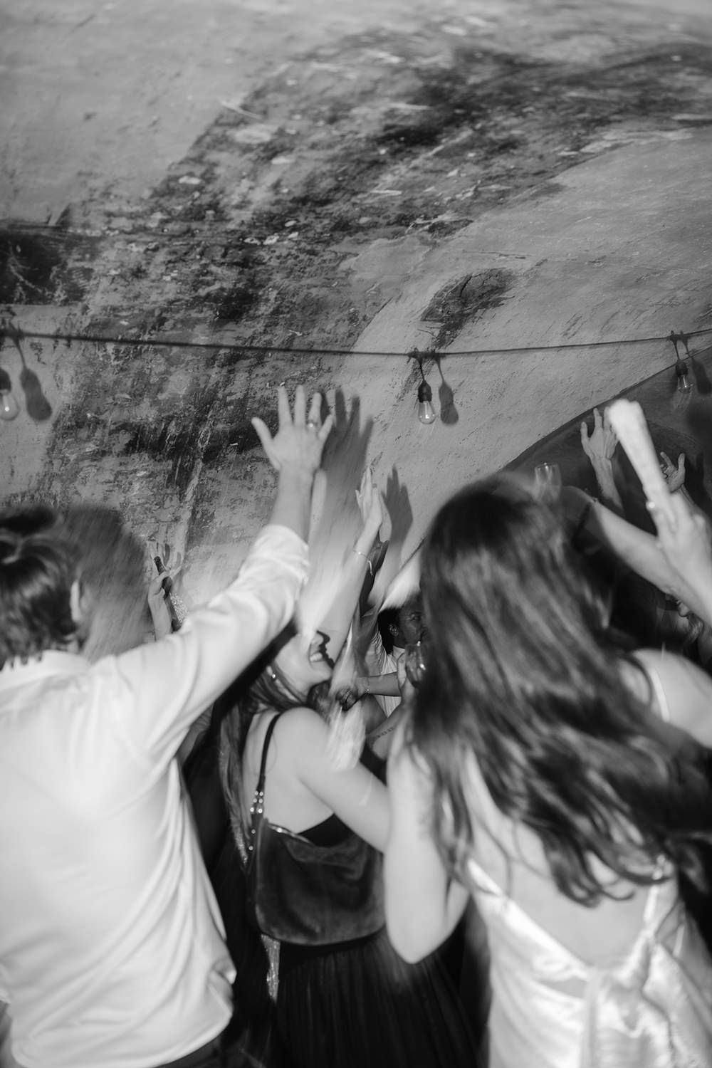 A sequence of black and white photos showing people raising their hands in a dimly lit space.
