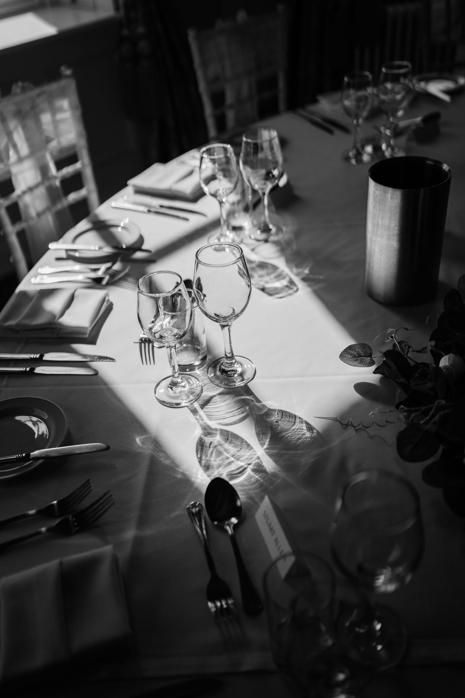 A wedding table with plates, glasses and cutlery styled with the sun casting a shadow across.