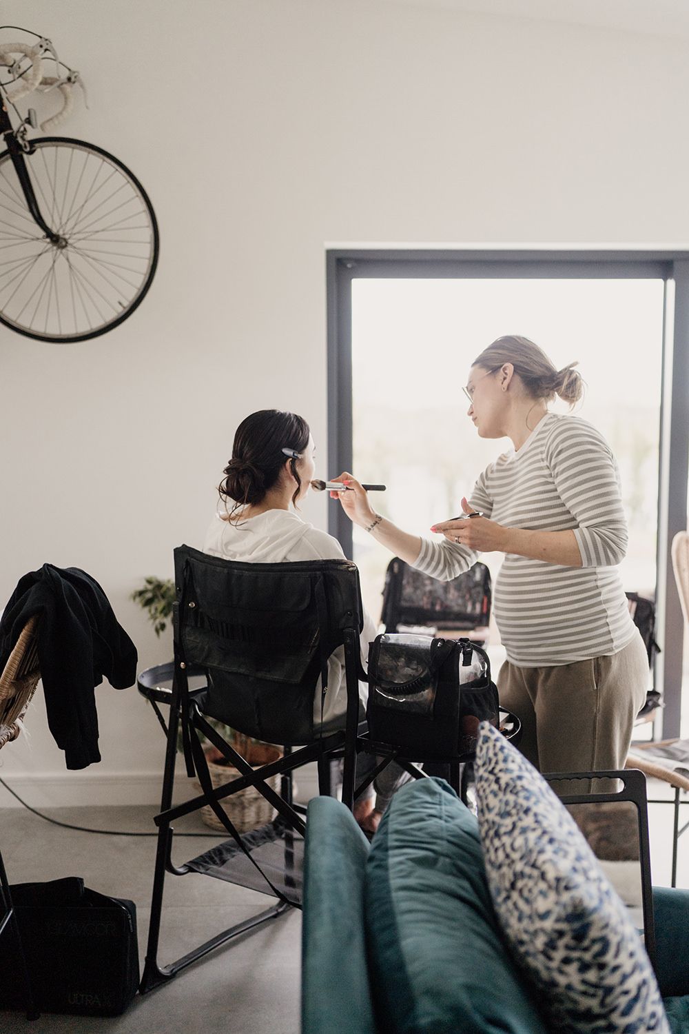 Bride sat in makeup chair on wedding morning having makeup done.