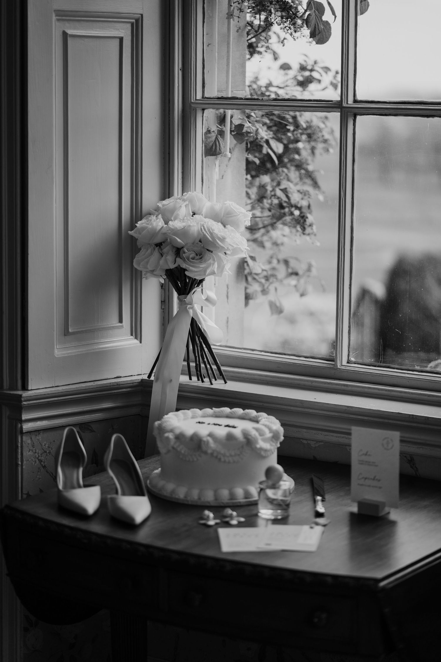 Black and white image of wedding day details, featuring flowers, cake, jewellery.