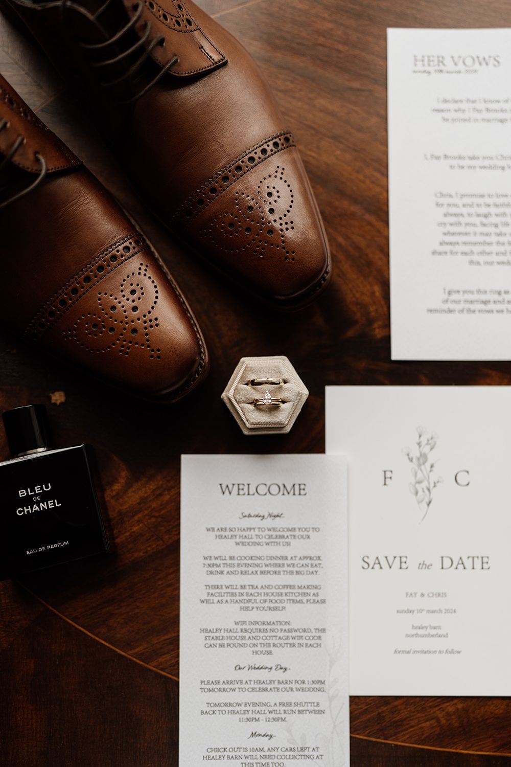 Wedding rings in box with wedding invites and vows around.
