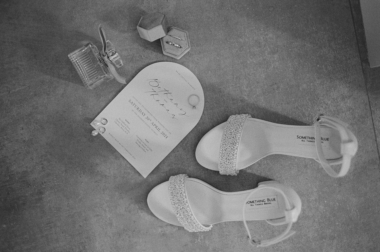 Black and white image of wedding invite, jewellery and shoes on 35mm film.