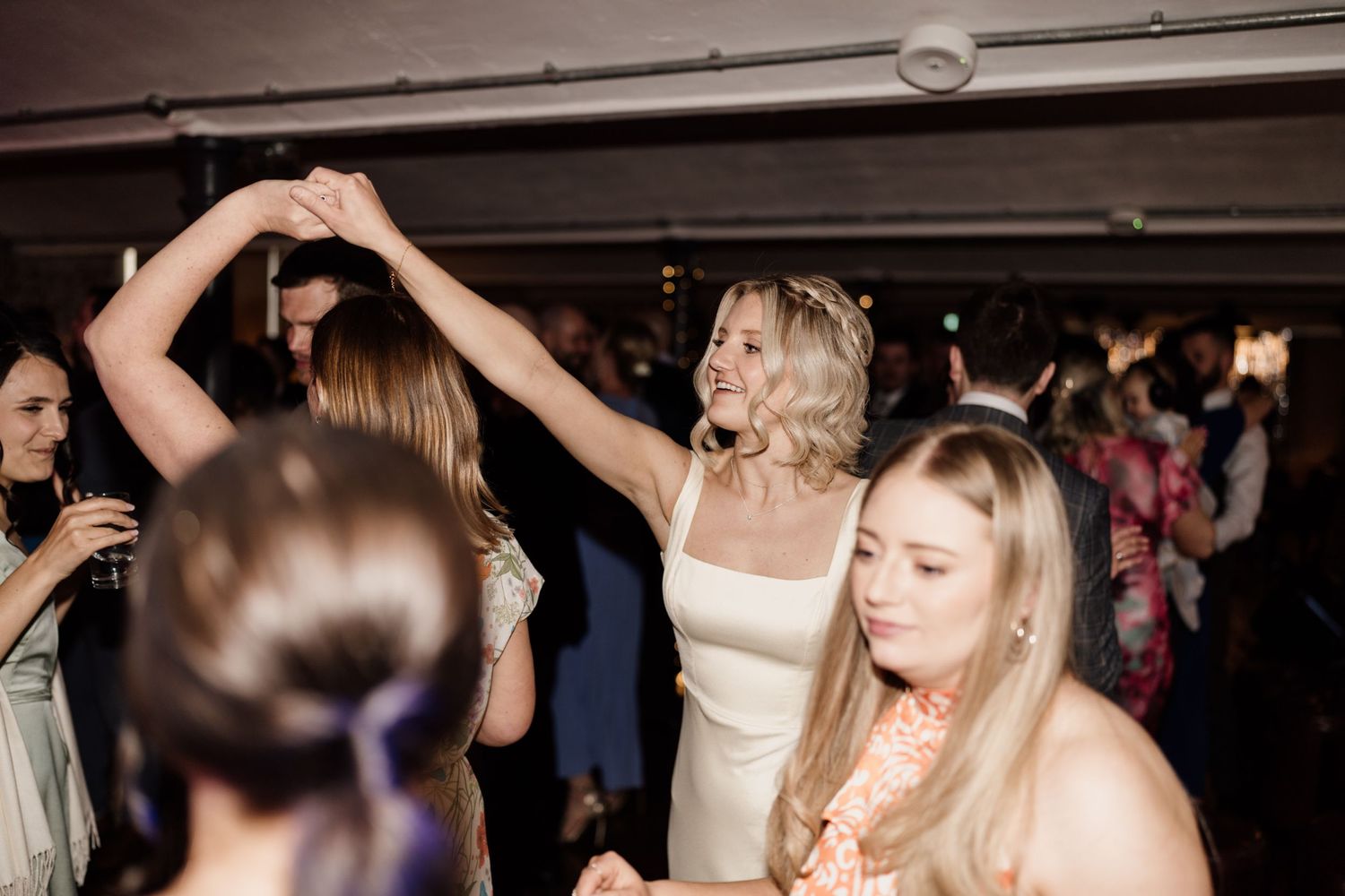 Wedding reception dance floor with guests celebrating and dancing.