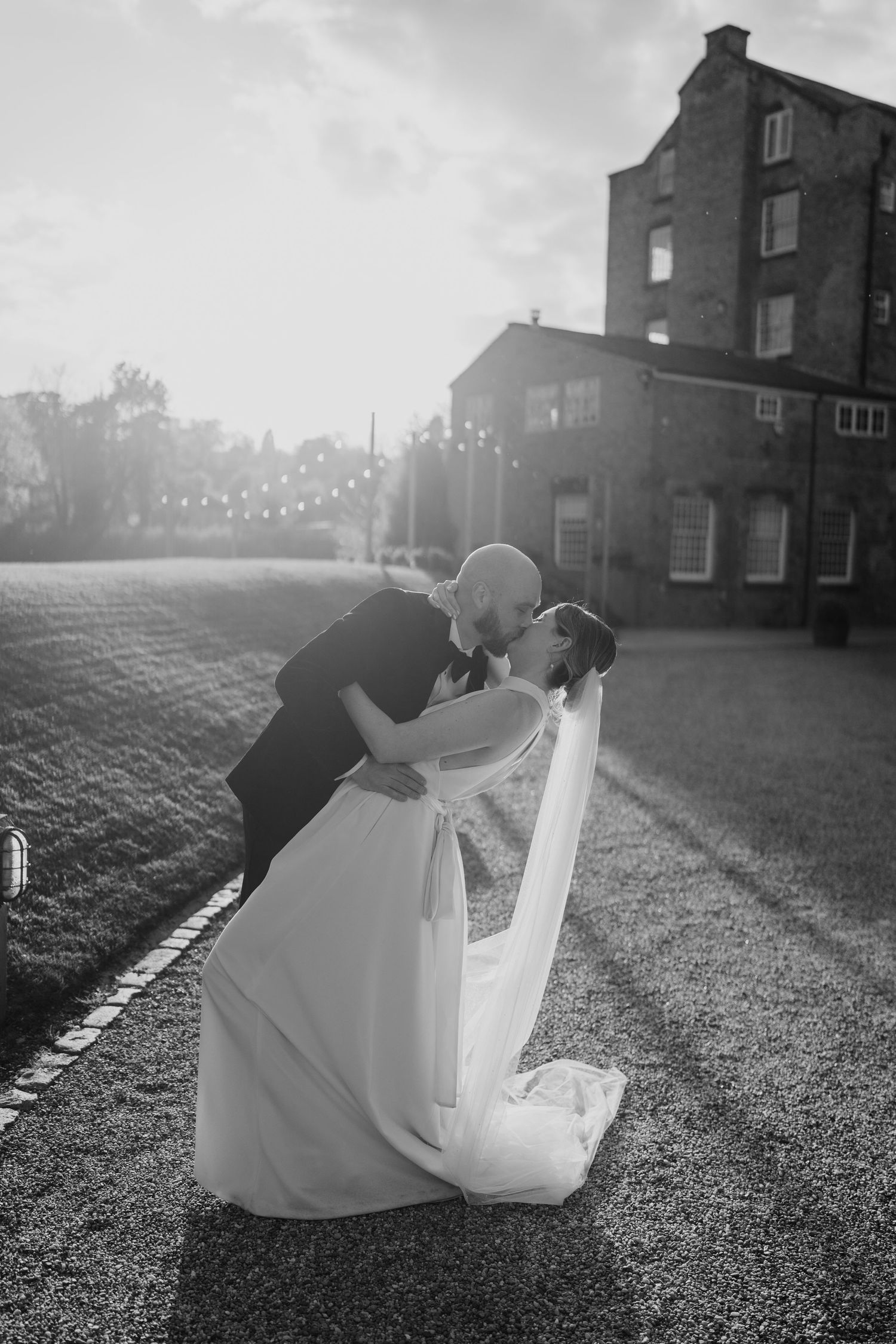 Dramatic black and white dip pose outside historic venue with flowing wedding dress.