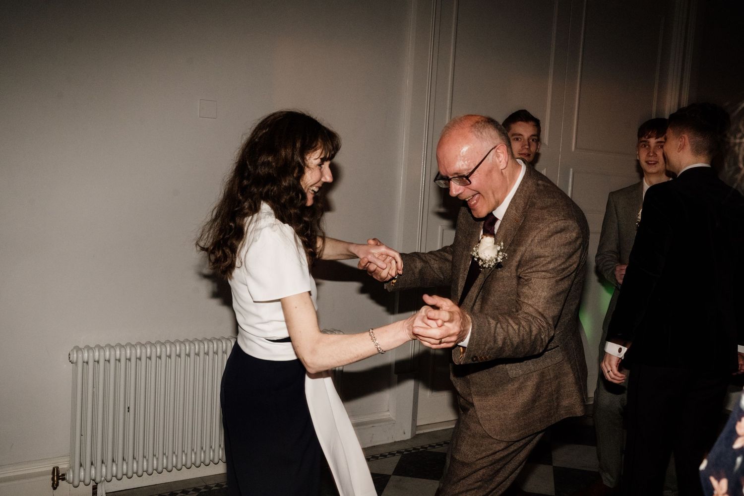 Mother and father of groom dancing with friends at wedding party.