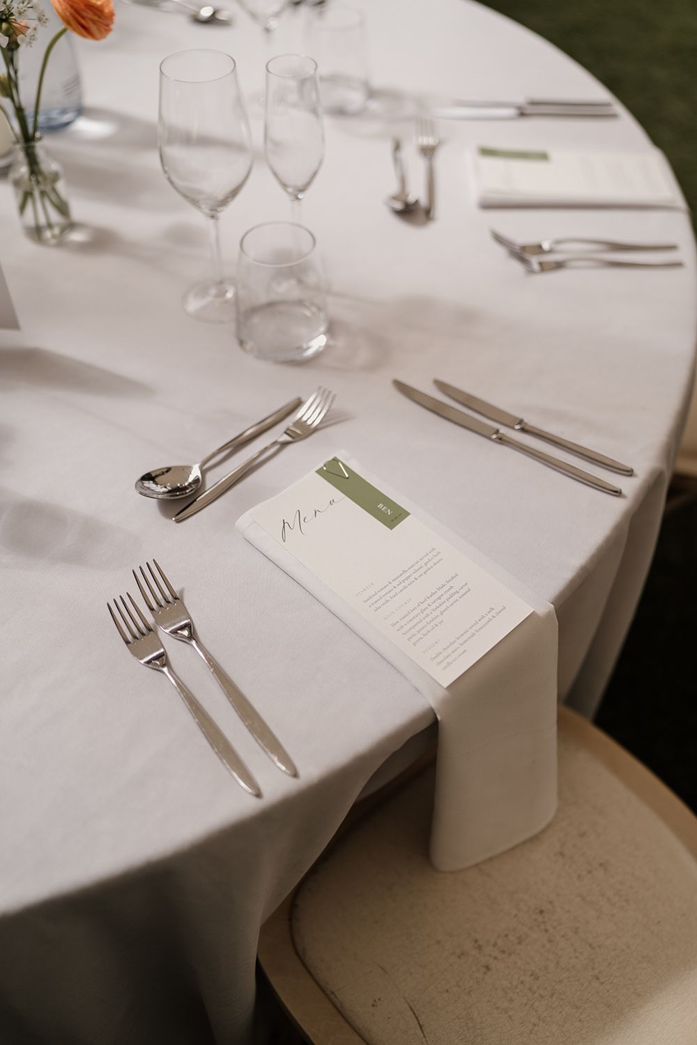 Wedding reception table with a white table cloth, minimal stationery and cutlery.