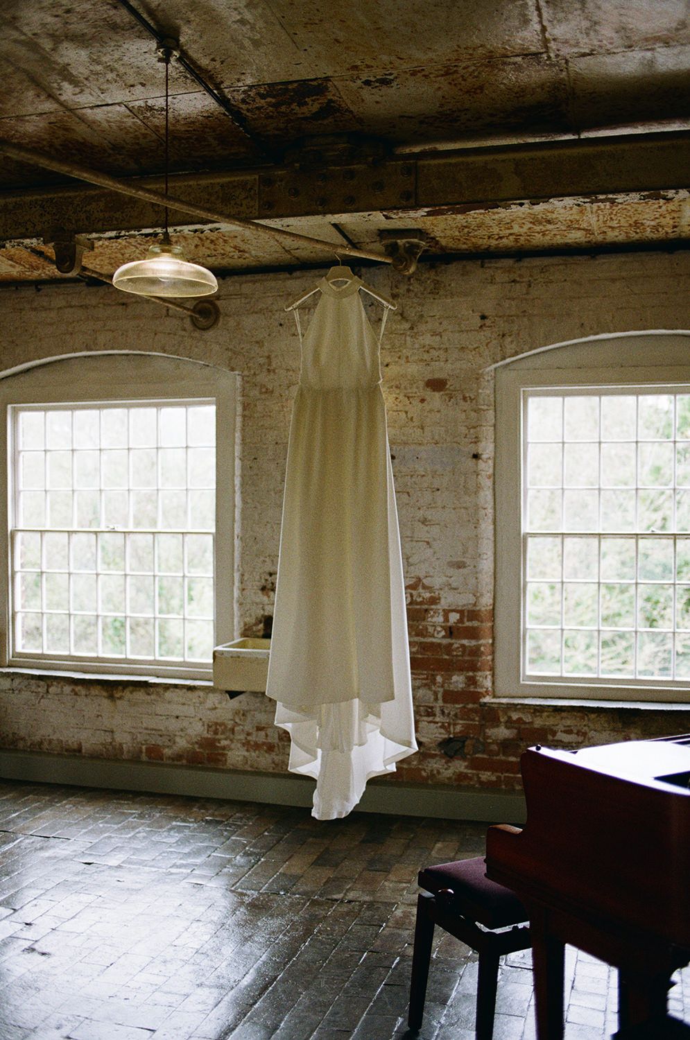 Brides white Jesus Perio wedding dress hung off a metal beam inside The West Mill.