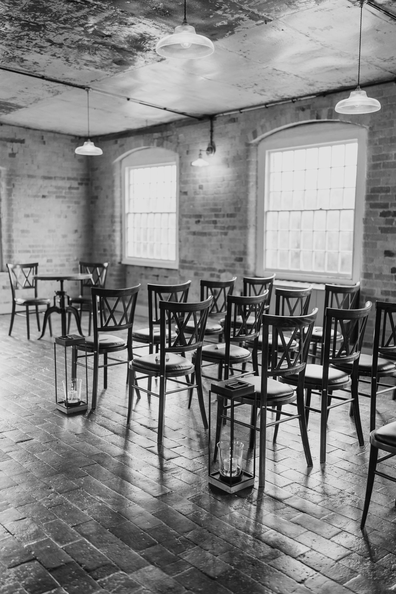 Black and white photo of empty chairs arranged for wedding ceremony in industrial venue.
